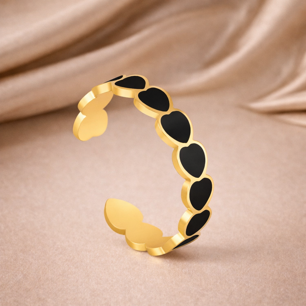 Gold bracelet with black stones on a beige fabric background