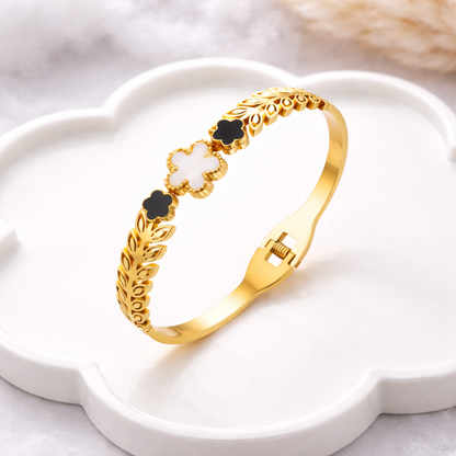 Gold bracelet with floral designs on a white dish