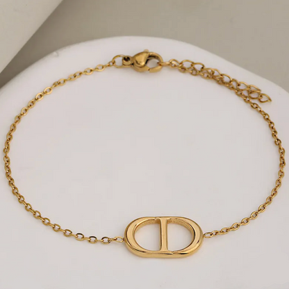 A gold-tone chain bracelet with a large interlocking D-shaped centerpiece, displayed on a white curved stand. The clasp and extender chain are visible, and text in the bottom right reads 'L:20cm+3cm'.