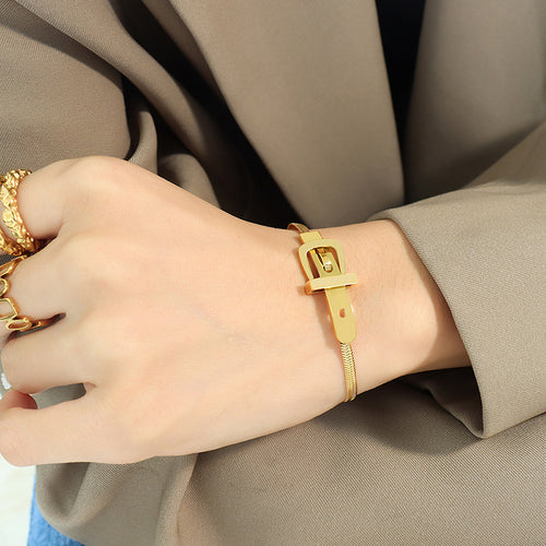 Gold bracelet on a wrist with a neutral background