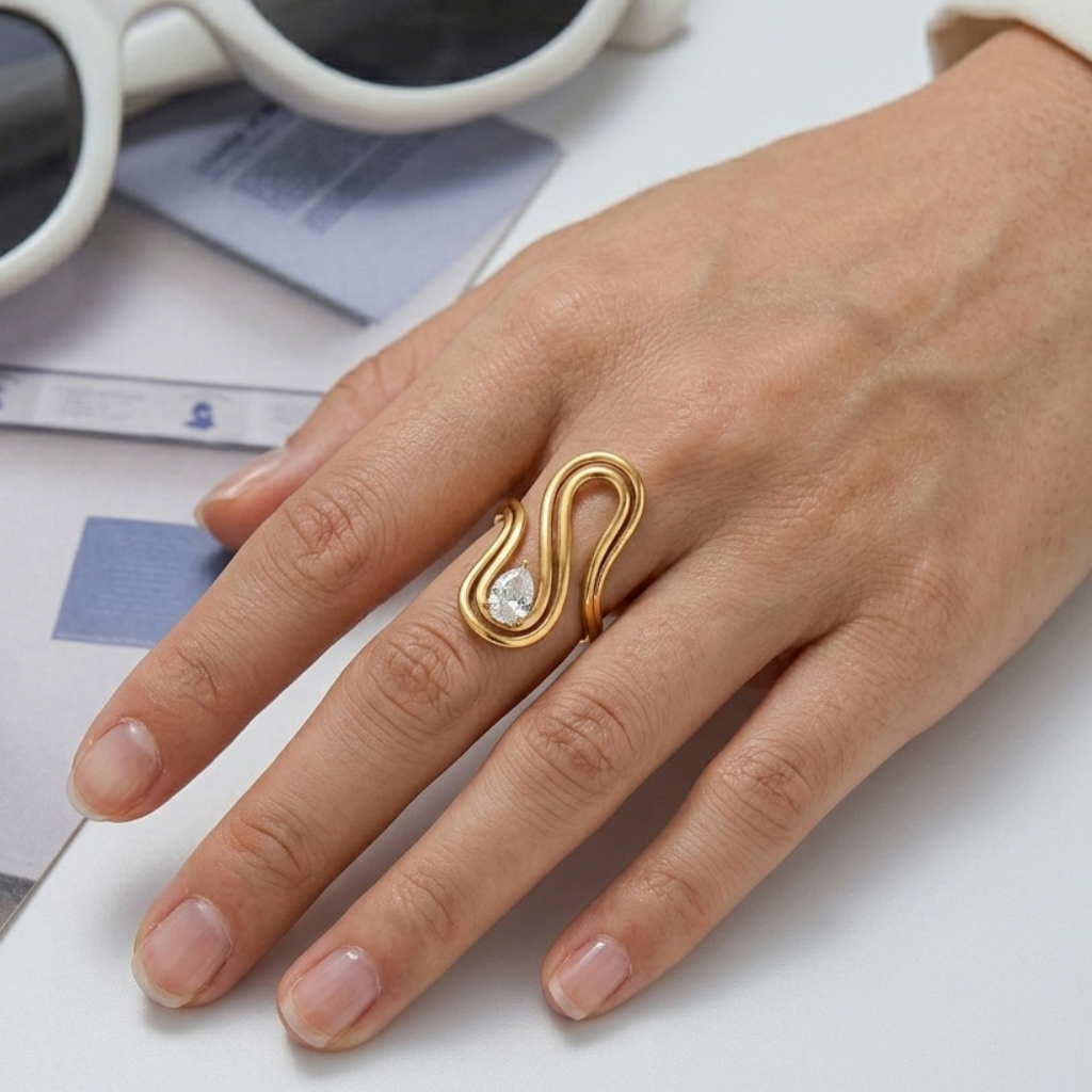 Hand wearing a gold ring with a diamond, sunglasses, and a magazine in the background