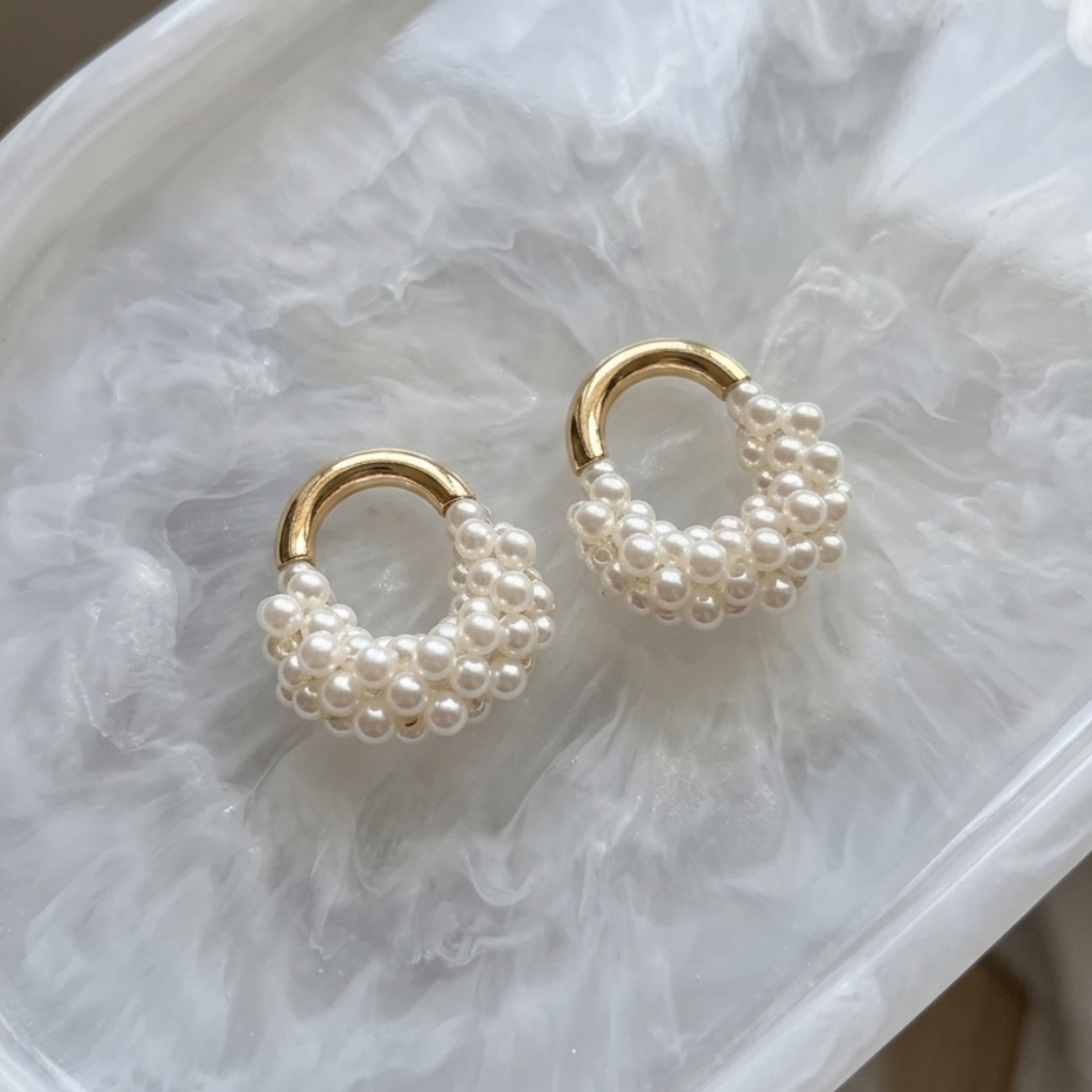 Pair of pearl hoop earrings on a marble surface