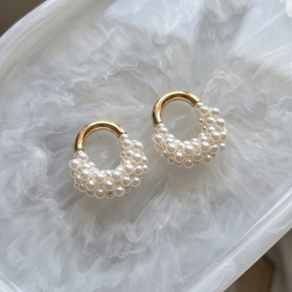 Pair of pearl hoop earrings on a marble surface