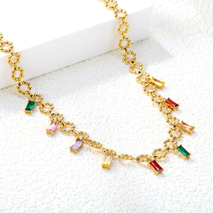 Gold necklace with colorful gemstone pendants on a white surface